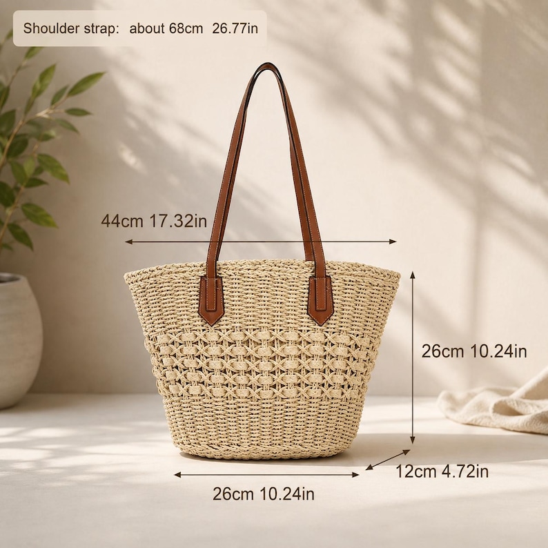 Pode incluir: Uma bolsa tote de palha tran&ccedil;ada bege com al&ccedil;as de couro marrom. A bolsa mede 44 cm de largura, 26 cm de altura e 12 cm de profundidade, com uma al&ccedil;a de 68 cm. O tran&ccedil;ado apresenta um padr&atilde;o decorativo em toda a superf&iacute;cie.