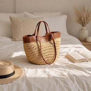 May include: A tote bag featuring a woven straw body with a tan, open-knit texture and a smooth brown leather upper section. The bag includes two matching brown leather handles attached to the top rim, providing a structured shape for this open-top accessory.