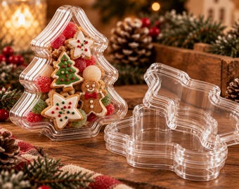 May include: A clear, tree-shaped plastic container filled with assorted festive biscuits, including gingerbread figures and star-shaped cookies with icing, alongside a matching empty tree-shaped container resting on its side.