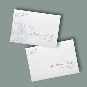May include: Two white rectangular envelopes featuring black printed text. One envelope displays a light blue floral illustration on the left side. Both envelopes show the return address for Marcelle & Tiffany and the recipient address for The Harper Family.