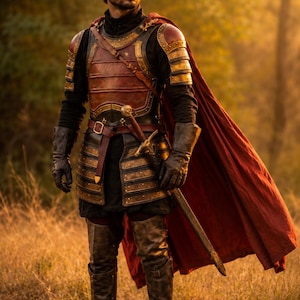 May include: A person wearing dark armor with red and gold accents, including a chest plate, shoulder pauldrons, and layered tassets. A long red cape hangs from the shoulders, and a sword with a gold hilt is strapped to the waist over a black tunic.
