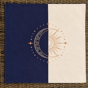 Peut inclure: Un tissu carré divisé verticalement en une moitié bleu marine foncé et une moitié crème. Au centre se trouve un motif linéaire couleur cuivre représentant un croissant de lune à gauche et un soleil avec des rayons sur la droite.