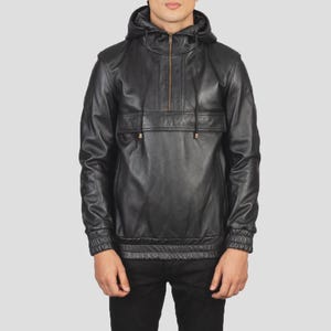 May include: A black leather pullover hoodie featuring a half-zip closure at the neckline, a large horizontal front pocket flap, long sleeves with ribbed cuffs, and a matching ribbed hem. The garment includes a hood with thin black drawstrings.