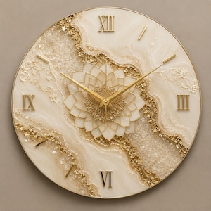 May include: A round wall clock featuring a cream-colored face with a central white lotus-like floral design. The clock face is accented with textured gold leaf and clear crystal-like fragments. It includes gold Roman numerals and thin gold hands.