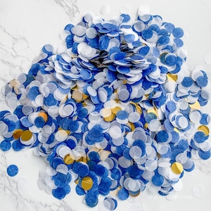 May include: A large pile of blue and white confetti with gold accents. The confetti is scattered on a white marble surface.