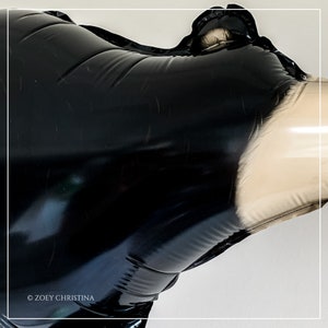 May include: Black and white inflatable orca whale balloon. The balloon is partially inflated and has a glossy finish.