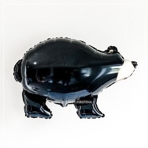 May include: Black balloon shaped like a bear with a white face. The balloon is inflated and ready to be used for a party or celebration.