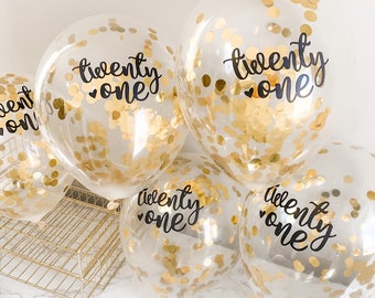 May include: Four clear balloons with gold confetti inside. Each balloon has a black script that says "twenty one" with a small heart symbol.