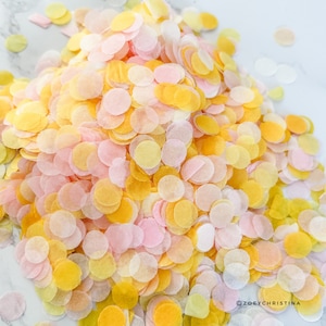 May include: A pile of confetti in shades of yellow, pink, and white. The confetti is made of tissue paper and is ideal for adding a festive touch to any celebration.
