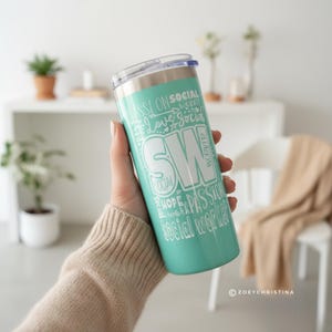 May include: A teal tumbler with a silver lid and the words "SW" in a large white font. The tumbler is covered in white text including "Passion", "Social", and "Social Worker".