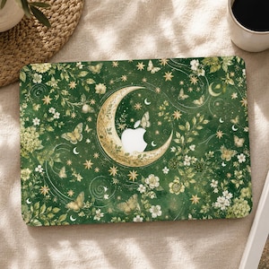 May include: A dark green laptop skin featuring a gold crescent moon centered around the Apple logo cutout. The design includes scattered gold stars, white flowers, and butterflies throughout the surface, creating a detailed botanical pattern.