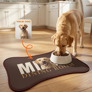 Könnte beinhalten: Eine knochenförmige, braune Futtermatte für Haustiere mit einem individuellen Foto eines gelben Labrador Retrievers und dem Text "DINING ROOM" in weißer und goldener Schrift. Ein weißer Napf mit Trockenfutter steht auf der Matte, ein Labrador frisst.