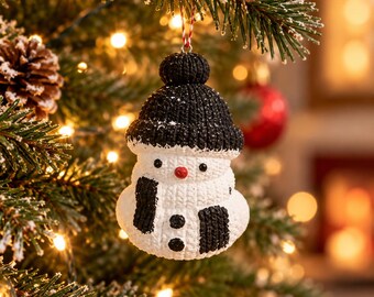 May include: A snowman Christmas tree ornament with a textured white body and a black knit-style hat. The snowman features a small red nose, black eyes, two black buttons on its torso, and black arm-like accents, hanging from a red and white string.