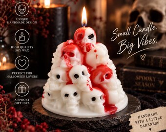 May include: A white candle shaped like a pyramid of skulls with red wax drips resembling blood. The candle features a single lit wick at the top. Text on the image includes "Small Candle. Big Vibes." and "HANDMADE WITH A LITTLE DARKNESS."