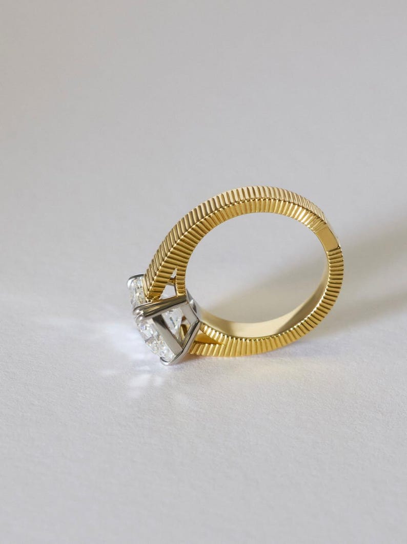 Peut inclure: Une bague en or dot&eacute;e d'un anneau textur&eacute; &agrave; rainures et d'une pierre pr&eacute;cieuse transparente &agrave; facettes mont&eacute;e sur un sertissage &agrave; griffes argent&eacute;. L'anneau pr&eacute;sente un motif de lignes verticales distinct qui fait le tour complet, contrastant avec l'int&eacute;rieur lisse et poli.