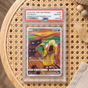 May include: A graded 2018 P.M. JPN. SM PROMO #286 Psyduck Munch: A Retrospective trading card in a clear plastic slab. The card features a yellow Psyduck with a wide-open mouth, two dark figures, and a colorful, swirling background design.