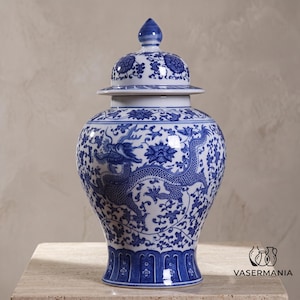 May include: A blue and white ceramic ginger jar featuring a detailed dragon motif and floral patterns. The vessel has a rounded body, a tapered base, and a removable lid with a pointed finial. The surface is decorated with intricate blue designs.