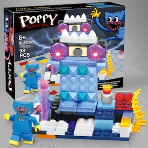 Può includere: Un set di costruzioni Poppy Playtime con un personaggio blu, una grande struttura a blocchi blu con occhi viola luminosi e denti bianchi, e una scatola nera con il testo Poppy Playtime, 6+, SL89200 e 98 PCS.