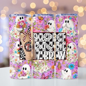 May include: A cylindrical tumbler featuring a repeating pattern of white ghosts holding colorful bouquets of flowers against a purple floral background. The design includes a graphic of a coffee cup and the text SUSPECT RUNS ON 7 BREW.