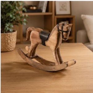May include: A wooden rocking horse featuring a natural light brown wood grain finish, a black leather-like saddle, and a black bridle. The horse is carved with visible joints and stands on two curved rockers, showcasing a smooth, polished surface.