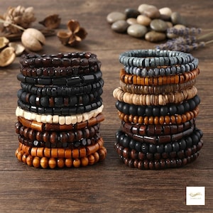 May include: Two stacks of beaded bracelets featuring a variety of wooden, matte black, and textured beads in shades of brown, black, grey, and cream. The bracelets are arranged in multiple rows, showcasing different bead shapes, sizes, and finishes.