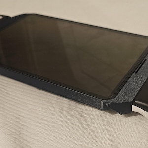 Può includere: Un controller di gioco portatile con una cornice blu scuro e impugnature laterali nere, dotato di pulsanti, joystick e comandi direzionali bianchi. Il dispositivo è progettato per sostenere un telefono cellulare o un tablet al centro.