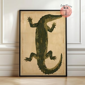 May include: A framed wall art print featuring a dark green, textured illustration of an alligator centred on a light beige background. The artwork includes a thin rectangular border and a small circular logo in the top right corner with the text Cozy Twins.