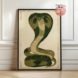 May include: A framed wall art print featuring a stylized illustration of a cobra snake in shades of dark green and cream. The snake is depicted in an upright, coiled position with its hood flared. The text Cozy Twins is visible in the top right.
