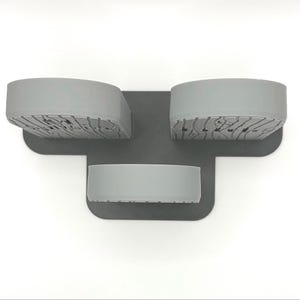 May include: A gray plastic organizer featuring three upright, semi-circular compartments attached to a flat, T-shaped base. The front faces of the two larger upper compartments display a textured, wood-grain pattern, while the lower compartment is smooth.