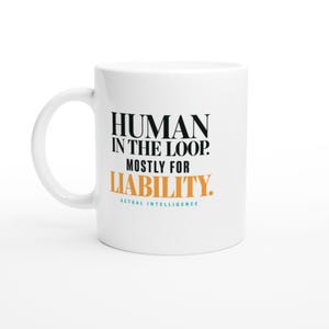 May include: A white ceramic mug featuring black, orange, and teal text. The text reads: HUMAN IN THE LOOP. MOSTLY FOR LIABILITY. ACTUAL INTELLIGENCE. The mug has a curved handle on the left side and a smooth, cylindrical body with a clean finish.