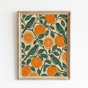 May include: A rectangular framed wall art print featuring a repeating pattern of dark green birds perched on branches with bright orange whole and sliced oranges against a light beige background. The print is enclosed in a light wood frame.