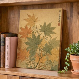 May include: A rectangular canvas print featuring a botanical illustration of maple leaves in shades of green and orange against a textured tan background, with vertical Japanese calligraphy and a small red seal in the upper right corner.
