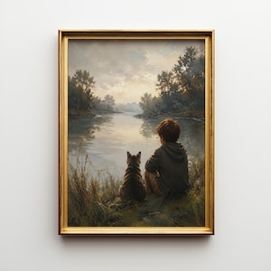 Könnte beinhalten: Ein gerahmter Kunstdruck, der eine Person in einem dunklen Kapuzenpullover und eine getigerte Katze zeigt, die nebeneinander an einem grasbewachsenen Ufer sitzen und bei Sonnenuntergang auf einen ruhigen Fluss mit Bäumen blicken.