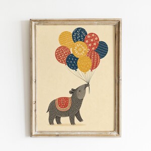 May include: A framed wall art print on a cream background featuring a dark gray tapir with a red patterned saddle, holding a cluster of nine colorful balloons in shades of red, yellow, and blue, each decorated with distinct white floral and geometric patterns.