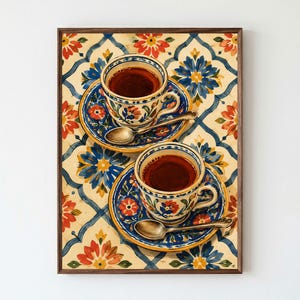 Könnte beinhalten: Ein gerahmter Wandkunstdruck mit zwei Keramik-Teetassen, gefüllt mit dunklem Tee, die jeweils auf einer passenden Untertasse mit einem silbernen Löffel stehen. Tassen und Untertassen zeigen ein florales Muster in Blau, Rot und Gelb.