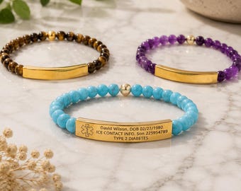 May include: Three beaded bracelets featuring gold-tone metal bars. One bracelet has turquoise beads, one has purple beads, and one has brown tiger eye beads. The turquoise bracelet is engraved with a medical symbol and personal information.