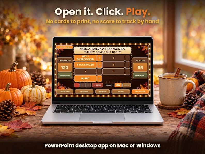 Laptop open on a wooden table displaying the Fall Friendly Feud game next to pumpkins, autumn leaves, and a mug of coffee.