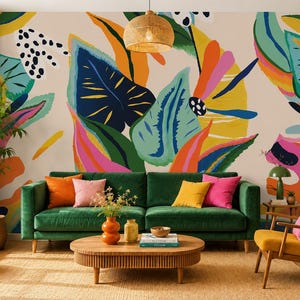 May include: A wall mural featuring a large-scale abstract botanical pattern with vibrant shapes in navy blue, yellow, orange, pink, and teal against a light beige background, positioned behind a dark green velvet sofa with colorful throw pillows.