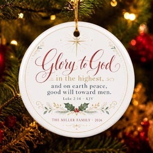 May include: A round white ceramic ornament featuring the red and black text Glory to God in the highest, and on earth peace, good will toward men. Luke 2:14 KJV. The design includes a gold star, green holly leaves, red berries, and The Miller Family 2026.