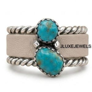 May include: A ring featuring a wide, smooth beige leather band flanked by two twisted silver-tone metal borders. Two oval, vibrant turquoise stones are set vertically in the center, held by silver-tone metal prongs, with the text JLUXEJEWELS.