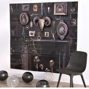 May include: A dark backdrop featuring a faux fireplace and a collection of gothic-themed decor. The display includes framed pictures, a ram skull, and various curiosities. Black balloons and a black chair are in the foreground, creating a spooky atmosphere.