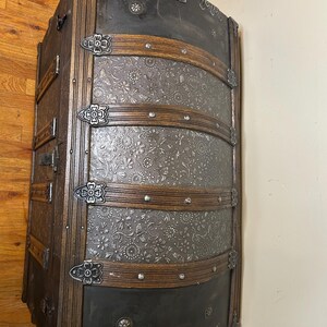 Refined walnut finish on solid wood banding of a large heritage storage chest.