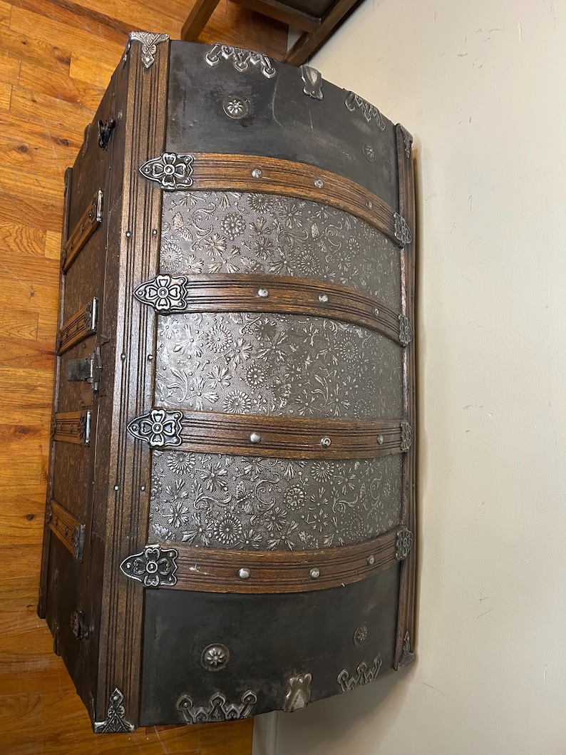 Refined walnut finish on solid wood banding of a large heritage storage chest.