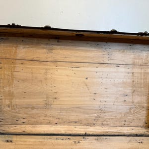 Puede incluir: Ba&uacute;l de madera antiguo abierto con interior marr&oacute;n claro. El ba&uacute;l tiene molduras y herrajes de metal oscuro. El interior est&aacute; hecho de tablas de madera de color claro. El ba&uacute;l est&aacute; abierto, revelando el interior.