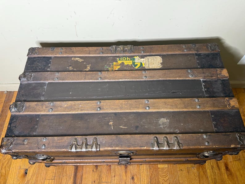 Top-down view of the flat lid highlighting the original wood banding, metal rivets, and weathered canvas surface
