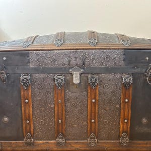 Large antique dome top trunk with a rare embossed tin pattern and oak slats.