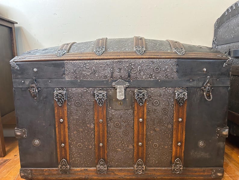 Large antique dome top trunk with a rare embossed tin pattern and oak slats.