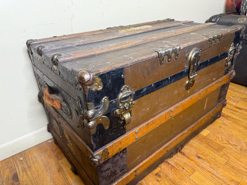 Front view of an authentic 1890s antique steamer trunk with original brown canvas, solid wood slats, and aged metal hardware.