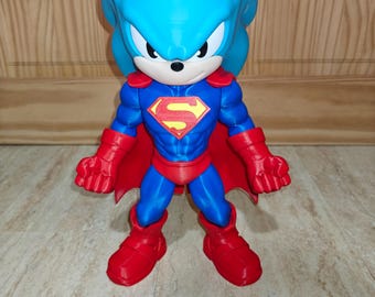 May include: A blue hedgehog-like figure wearing a blue and red superhero costume with a red cape and a yellow and red S-shaped emblem on the chest. The figure has large pointed ears, a black nose, and red gloves and boots, standing in a firm pose.
