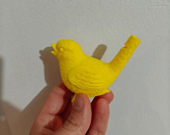 May include: A bright yellow bird-shaped whistle made of molded plastic. The whistle features detailed feather textures on the wings and body, with an open beak and a mouthpiece extending from the tail section, designed for producing sound.